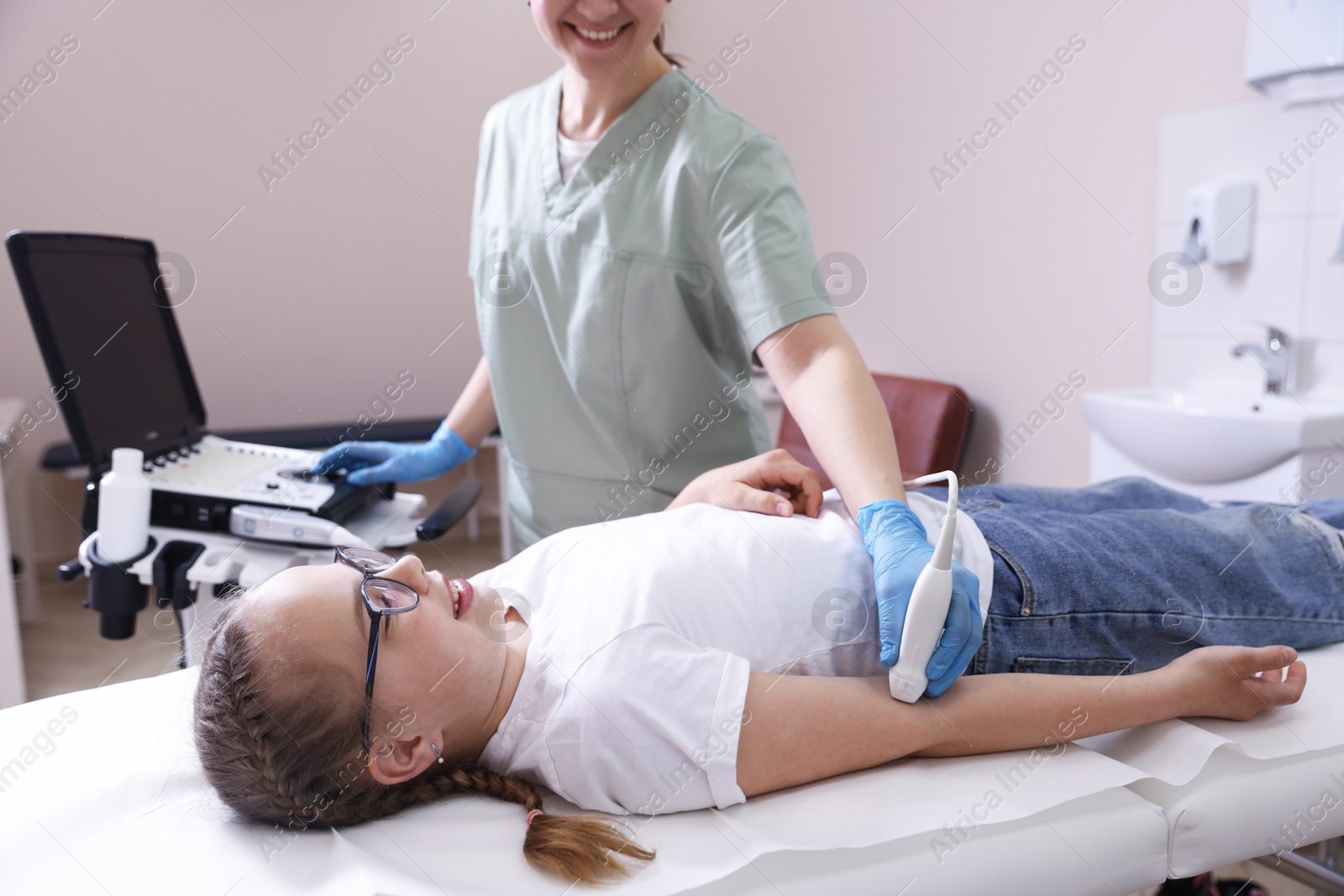 Sonographer conducting ultrasound examination of girl's arm in clinic, closeup Photo of Sonographer conducting ultrasound examination of girl's arm in clinic, closeup