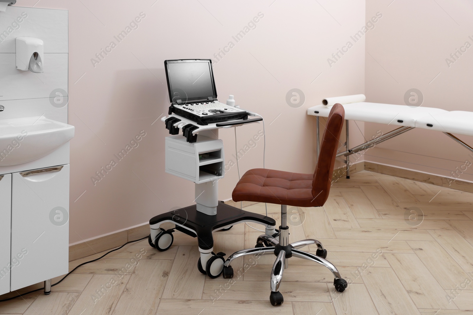 Modern ultrasound machine, chair and examination bed in clinic Photo of Modern ultrasound machine, chair and examination bed in clinic
