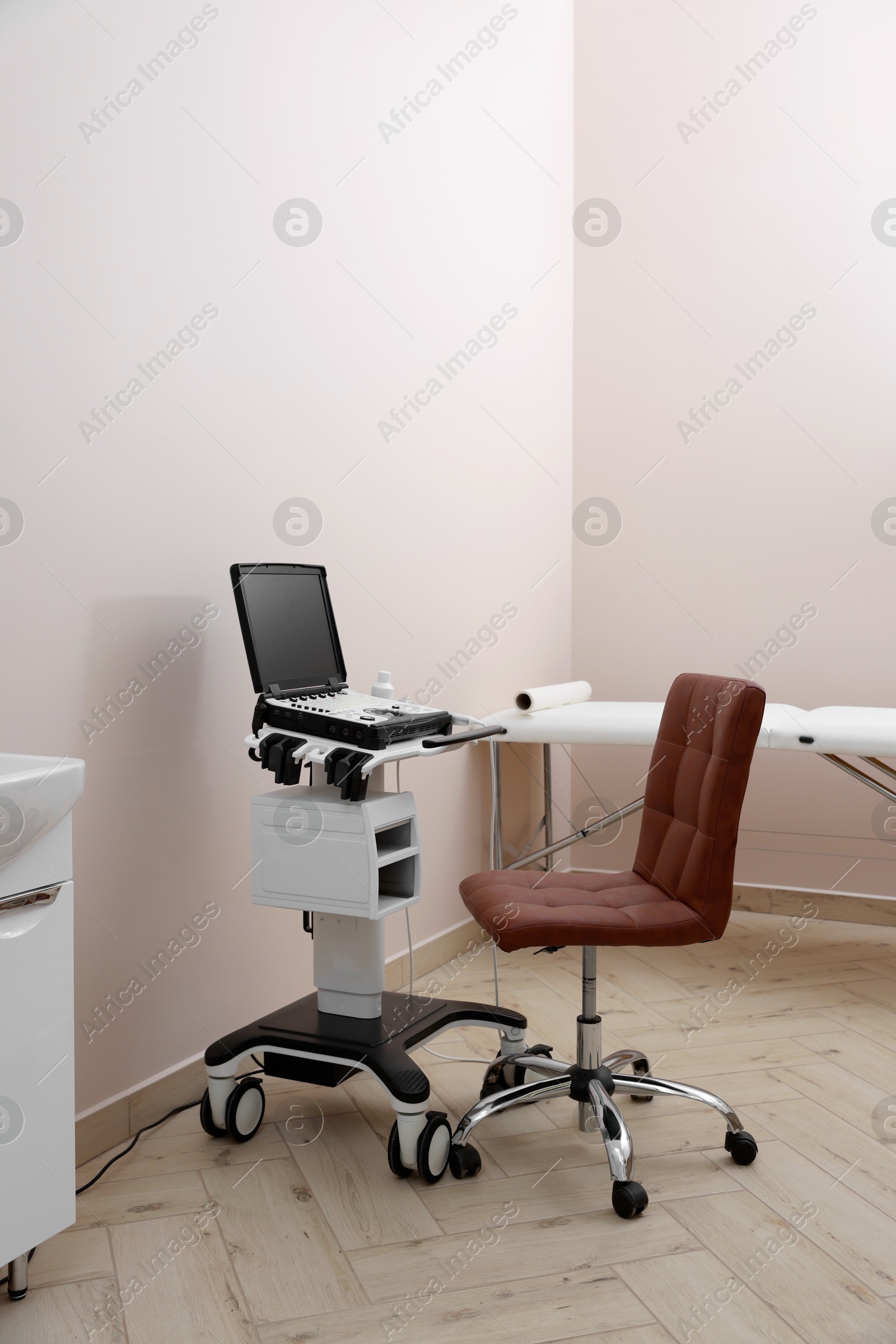 Modern ultrasound machine, chair and examination bed in clinic Photo of Modern ultrasound machine, chair and examination bed in clinic