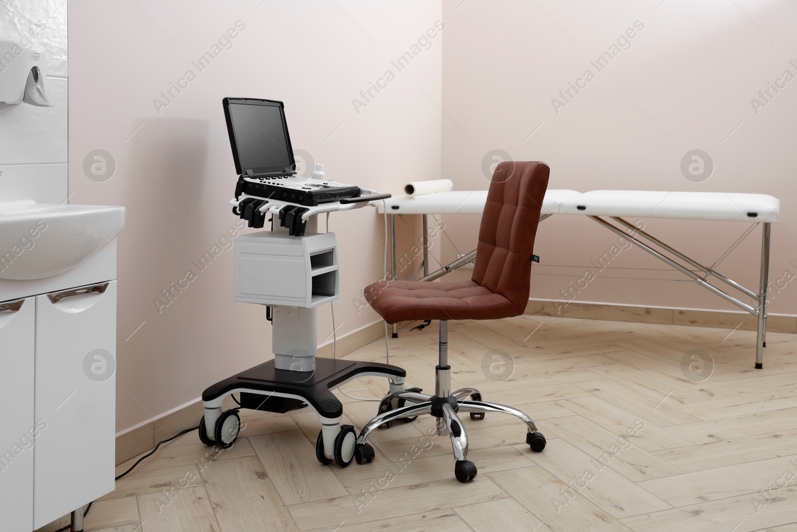 Modern ultrasound machine, chair and examination bed in clinic Photo of Modern ultrasound machine, chair and examination bed in clinic