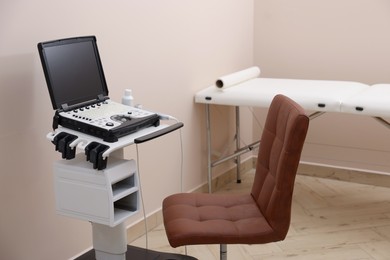 Photo of Modern ultrasound machine, chair and examination bed in clinic