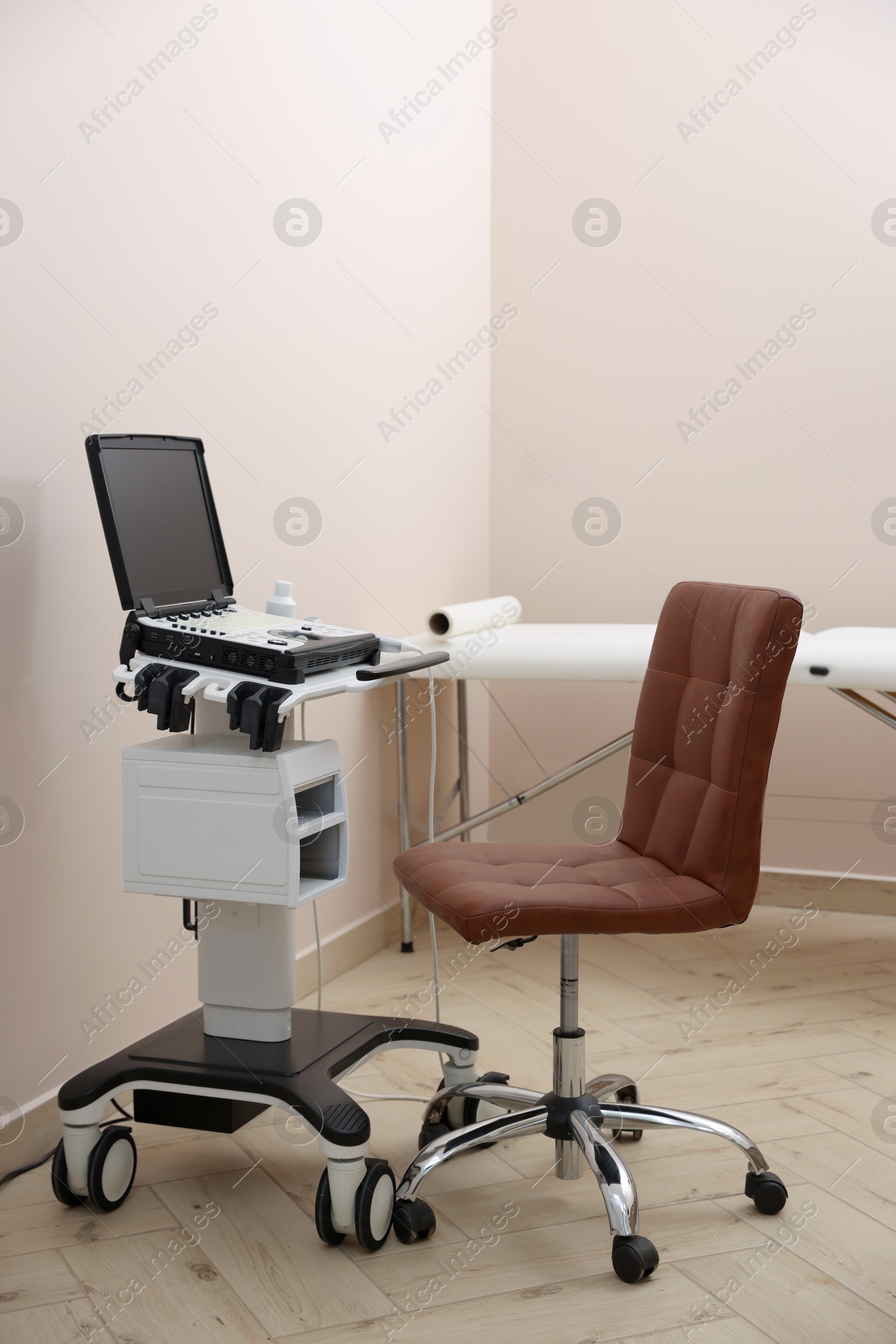 Modern ultrasound machine, chair and examination bed in clinic Photo of Modern ultrasound machine, chair and examination bed in clinic