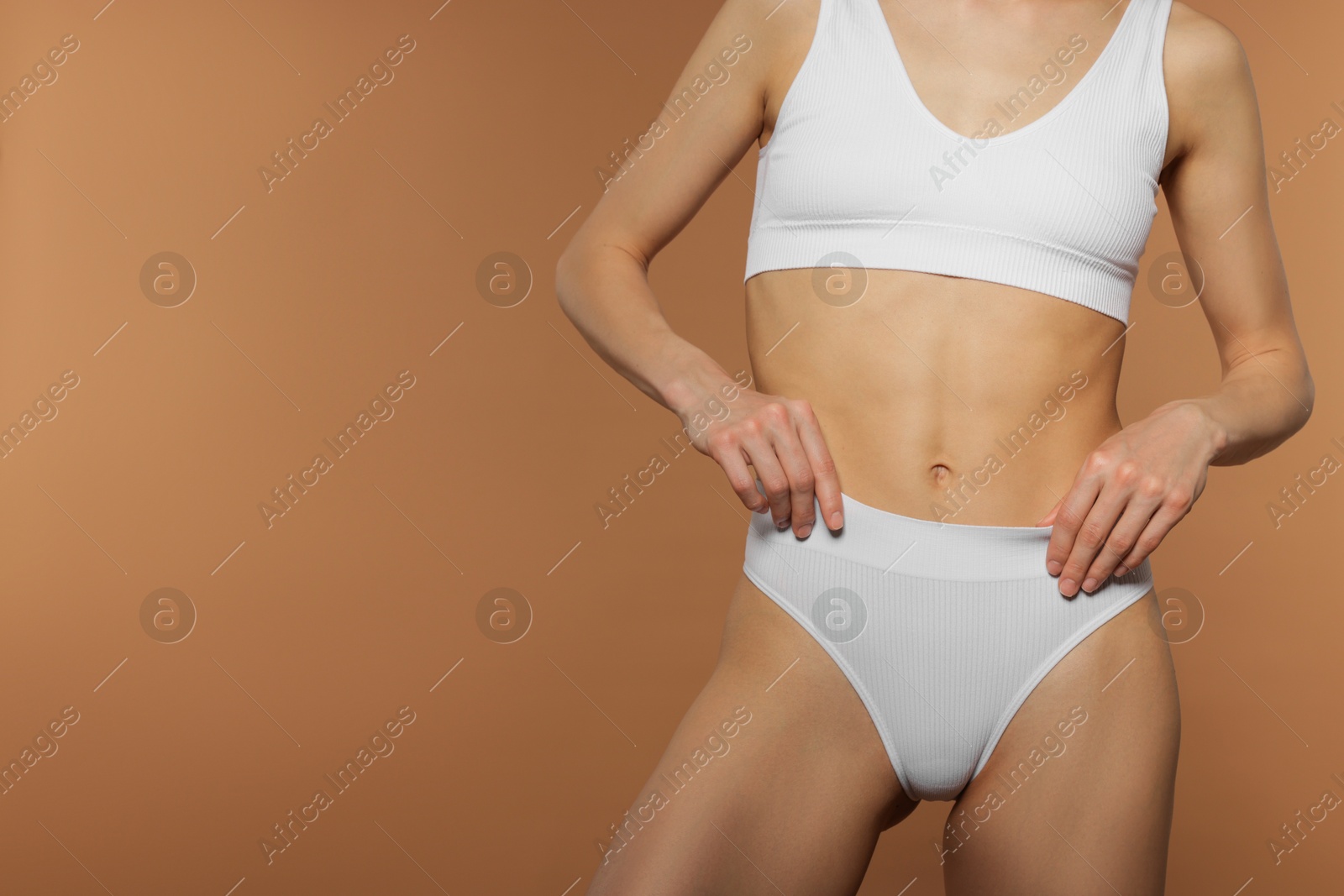 Woman with perfect slim body on beige background, closeup. Space for text Photo of Woman with perfect slim body on beige background, closeup. Space for text