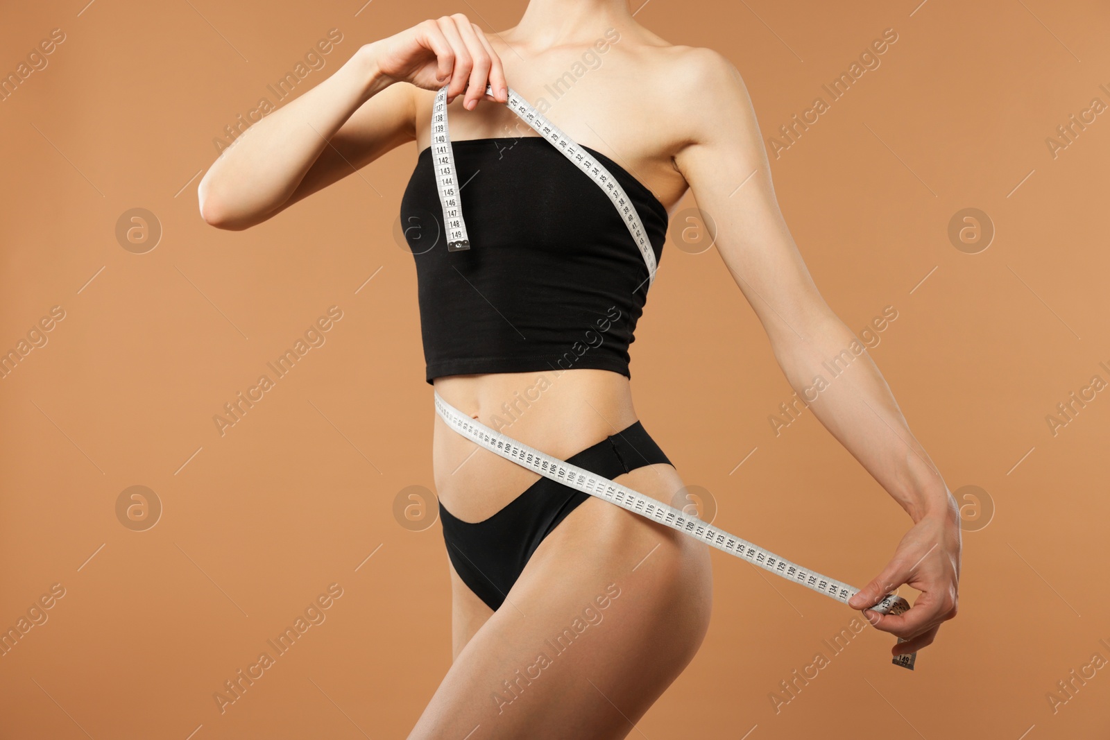 Woman with slim body and measuring tape on beige background, closeup Photo of Woman with slim body and measuring tape on beige background, closeup