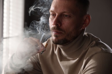 Photo of Man smoking cigarette near window in room