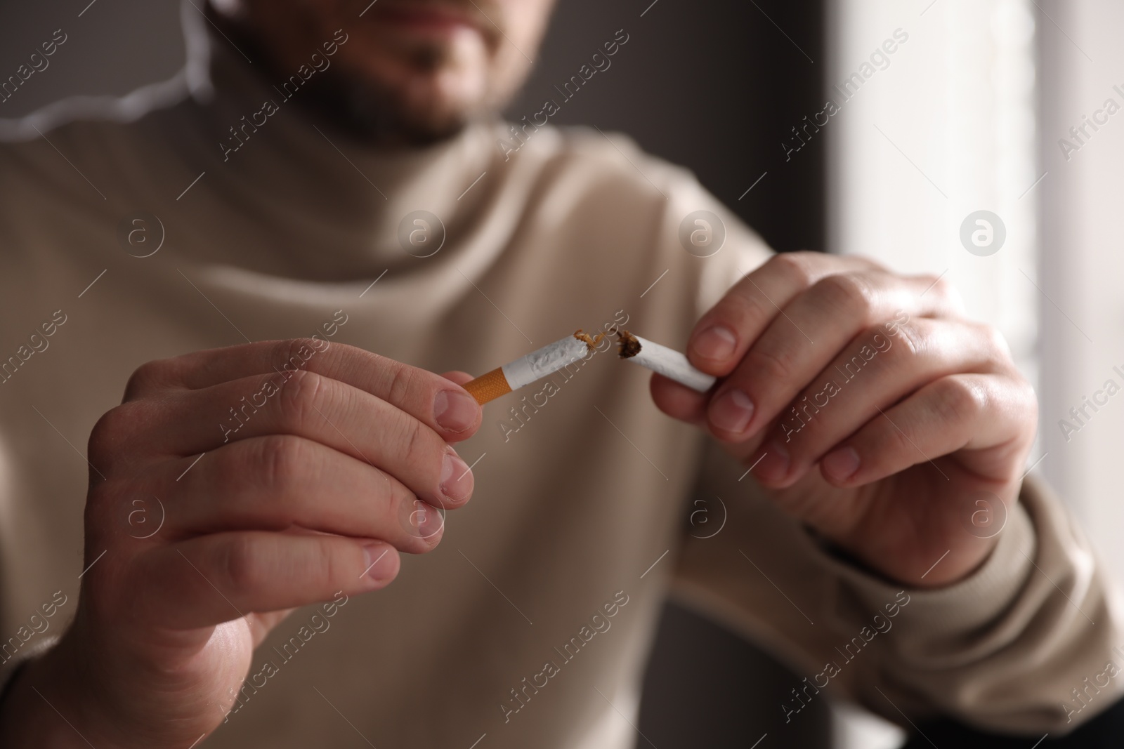 Man holding broken cigarette on blurred background, closeup. Stop smoking Photo of Man holding broken cigarette on blurred background, closeup. Stop smoking