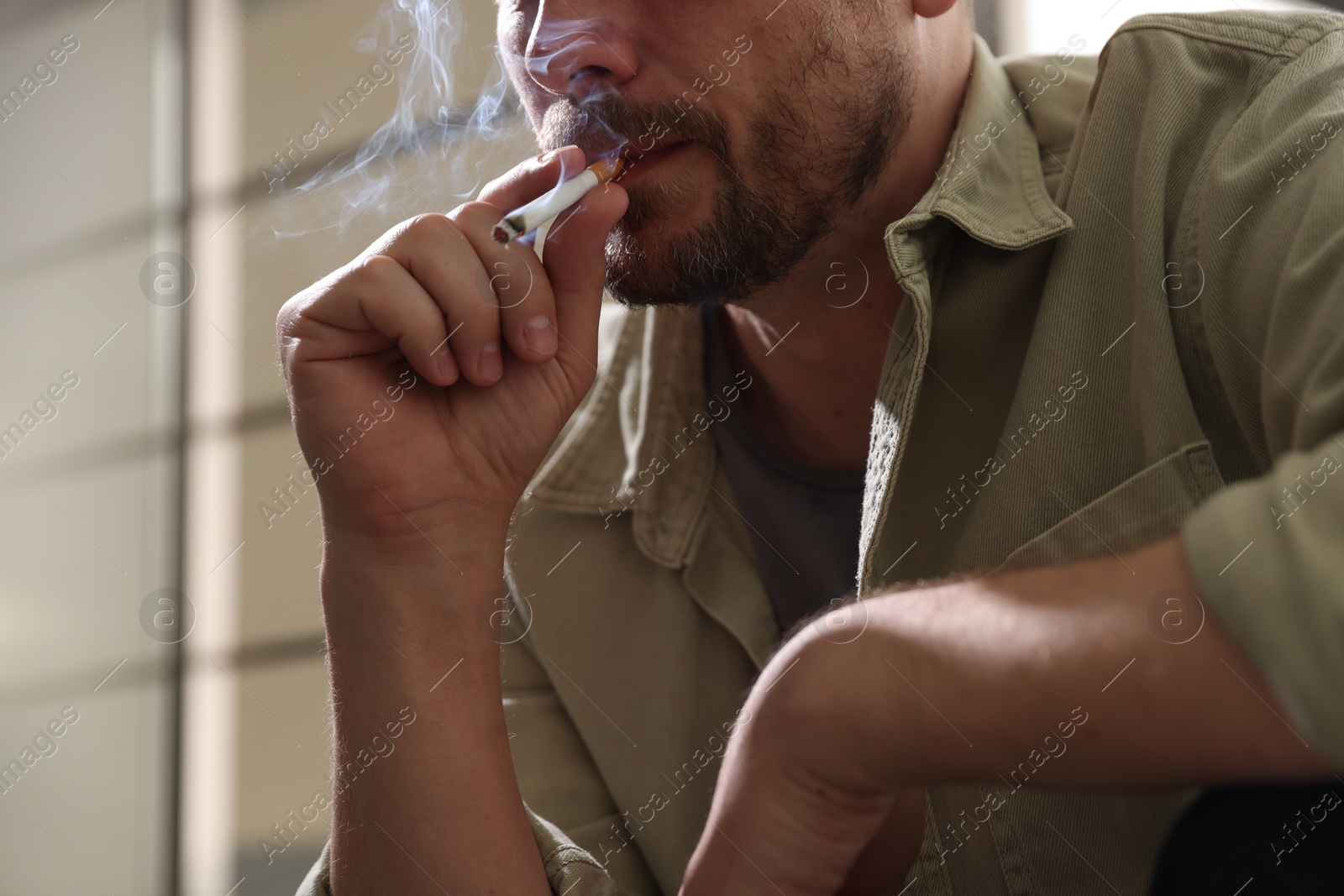 Man smoking cigarette on blurred background, closeup Photo of Man smoking cigarette on blurred background, closeup