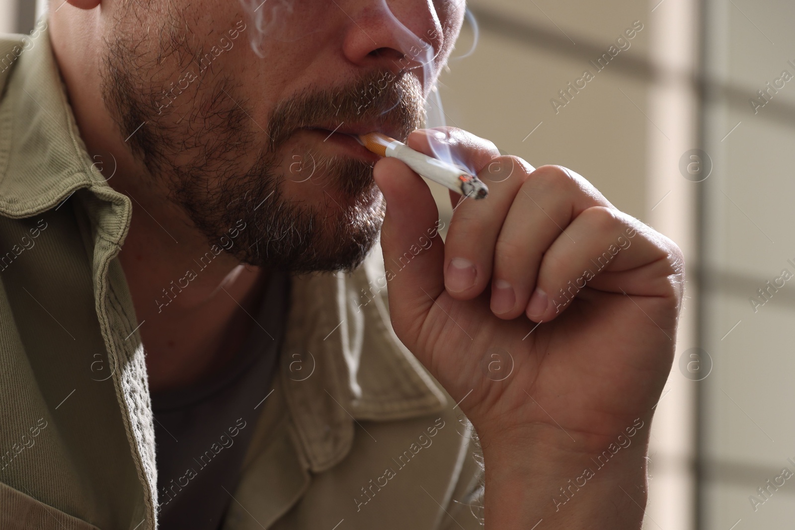 Man smoking cigarette on blurred background, closeup Photo of Man smoking cigarette on blurred background, closeup