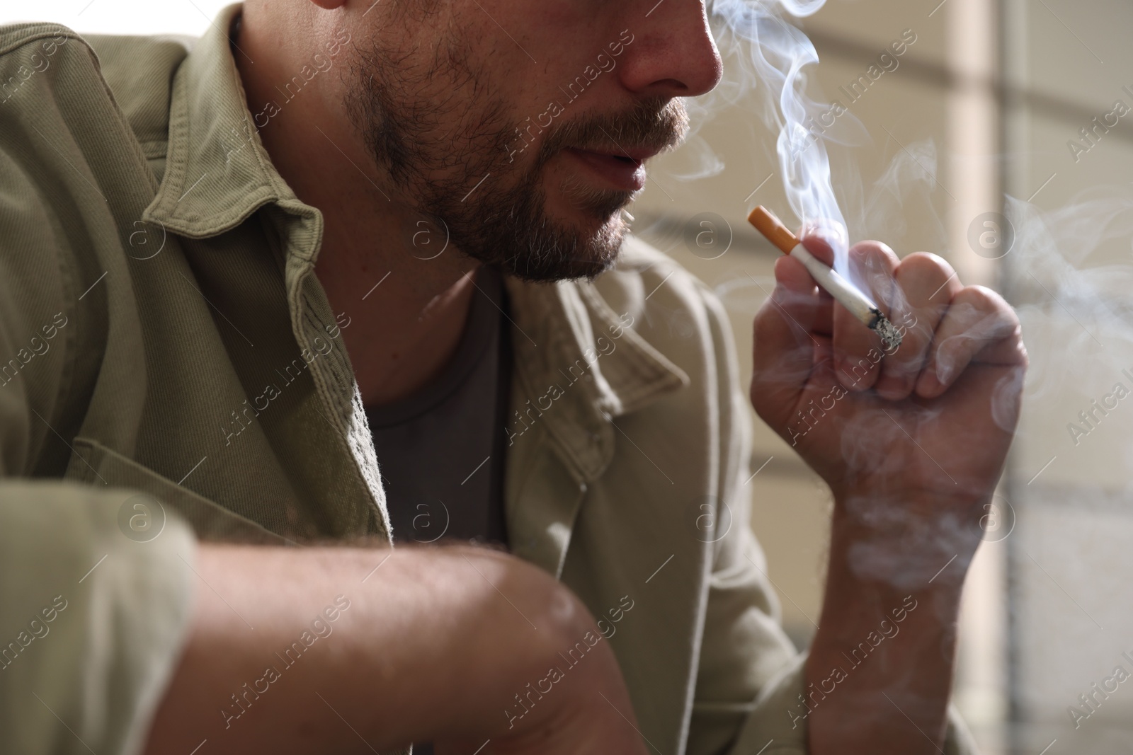 Man smoking cigarette on blurred background, closeup Photo of Man smoking cigarette on blurred background, closeup