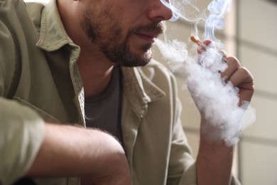 Photo of Man smoking cigarette on blurred background, closeup