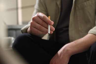 Photo of Man smoking cigarette on blurred background, closeup