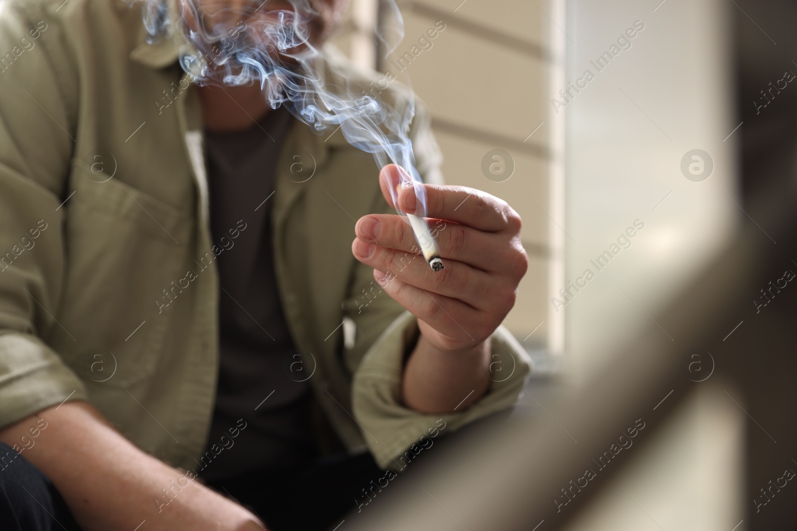Man smoking cigarette on blurred background, closeup Photo of Man smoking cigarette on blurred background, closeup