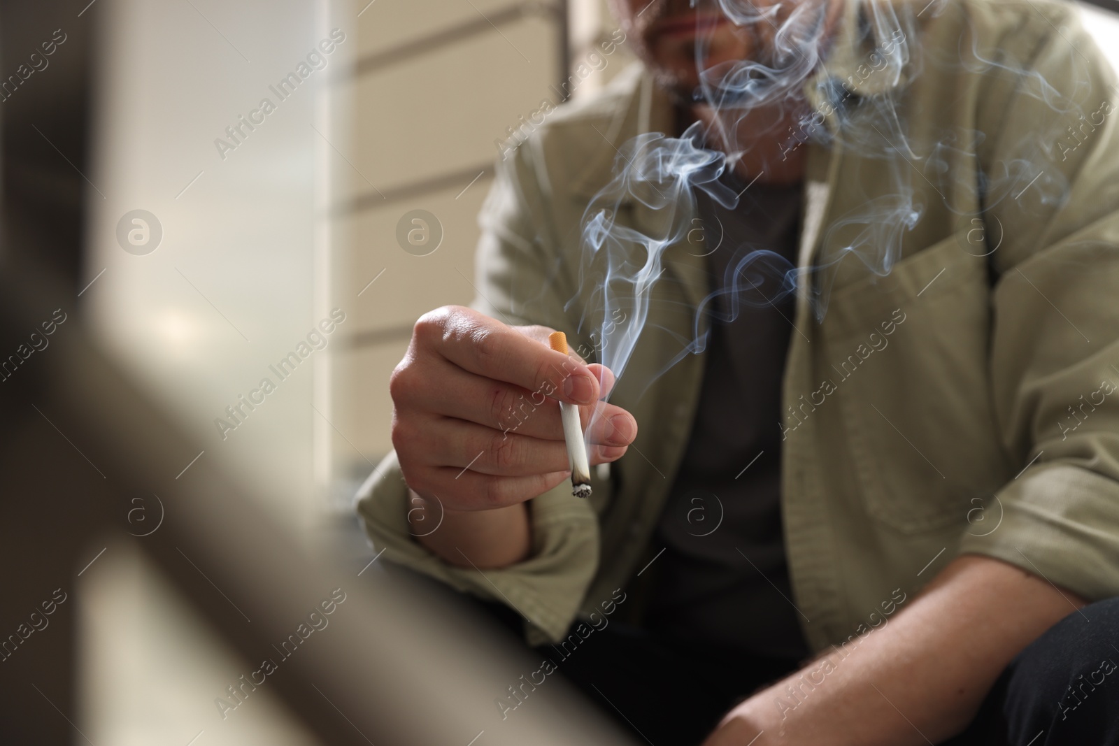 Man smoking cigarette on blurred background, closeup Photo of Man smoking cigarette on blurred background, closeup