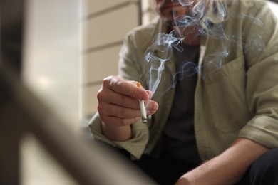 Photo of Man smoking cigarette on blurred background, closeup