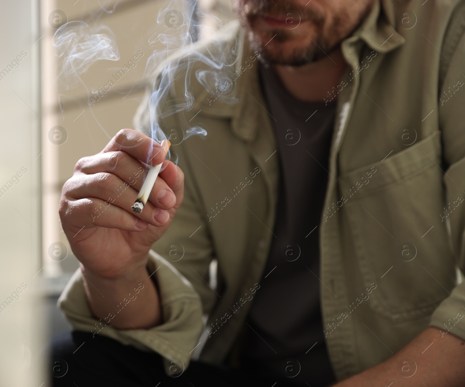 Man smoking cigarette on blurred background, closeup Photo of Man smoking cigarette on blurred background, closeup