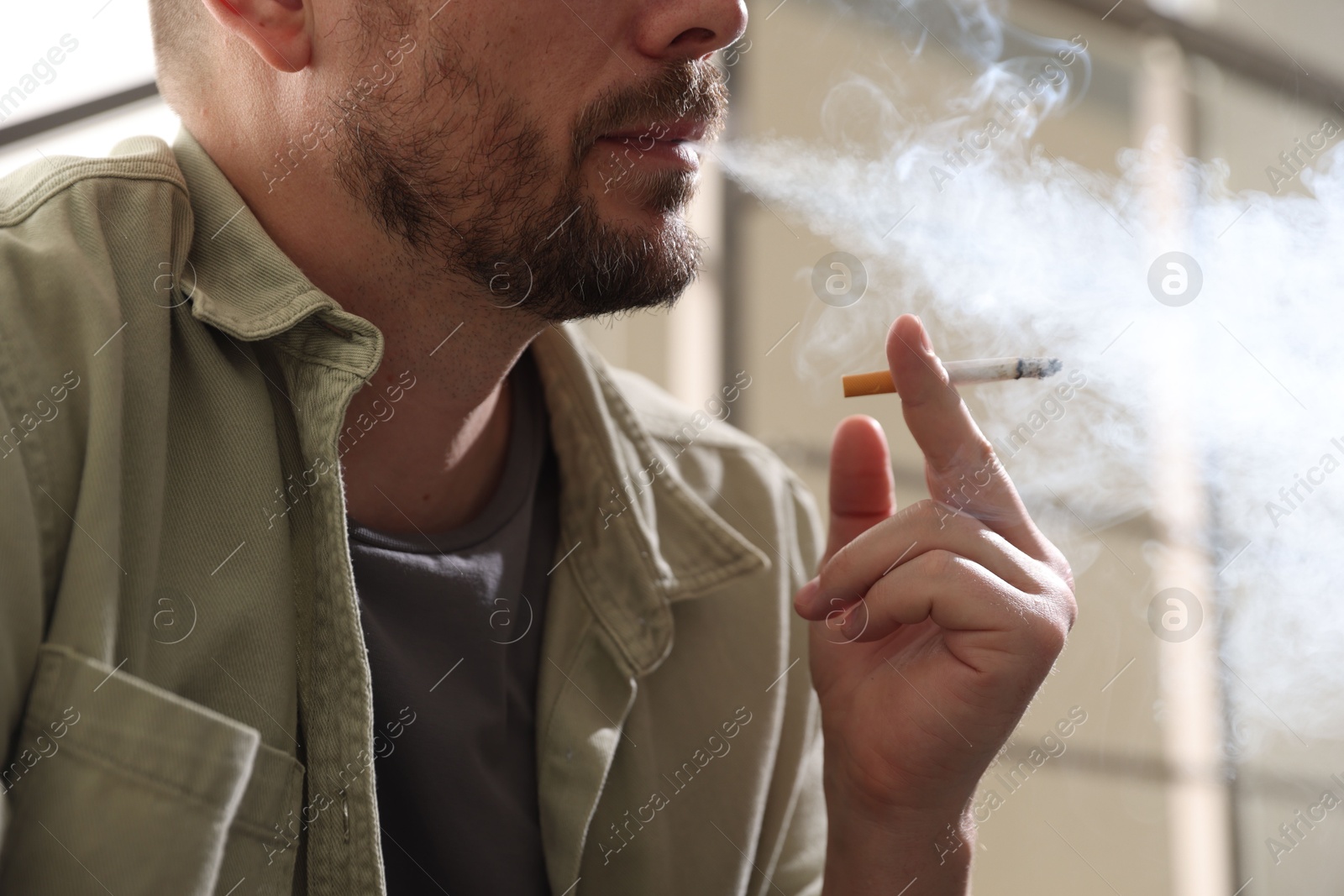 Man smoking cigarette on blurred background, closeup Photo of Man smoking cigarette on blurred background, closeup