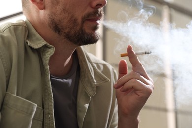 Photo of Man smoking cigarette on blurred background, closeup