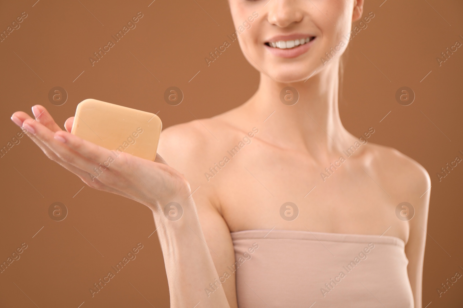 Smiling woman with soap bar on brown background, closeup Photo of Smiling woman with soap bar on brown background, closeup