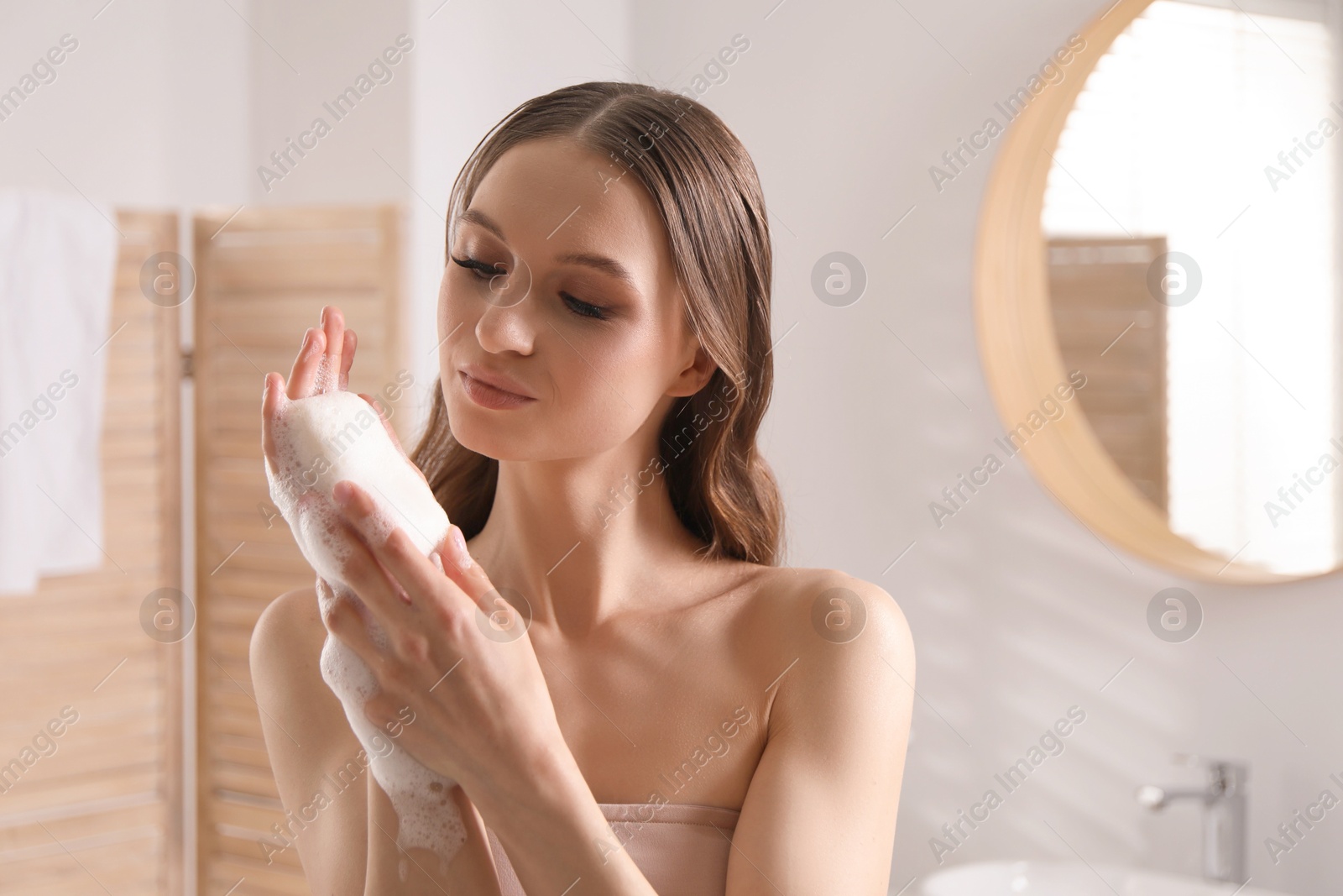 Beautiful woman with foaming soap bar in bathroom Photo of Beautiful woman with foaming soap bar in bathroom
