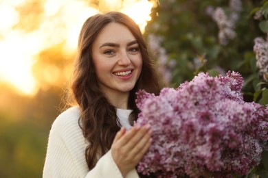 Photo of Portrait of smiling woman with lilac flowers outdoors in morning