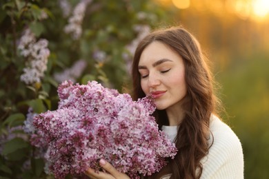 Photo of Beautiful woman with bouquet of lilac flowers in morning