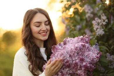 Photo of Portrait of smiling woman with lilac flowers outdoors in morning