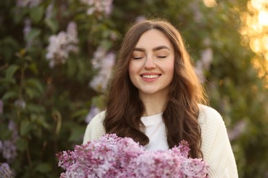 Photo of Portrait of smiling woman with lilac flowers outdoors in morning