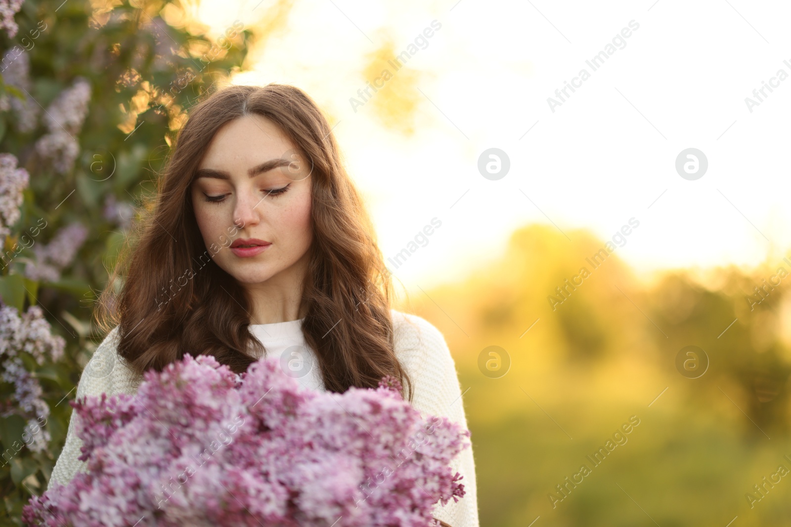 Beautiful woman with lilac flowers outdoors in morning. Space for text Photo of Beautiful woman with lilac flowers outdoors in morning. Space for text