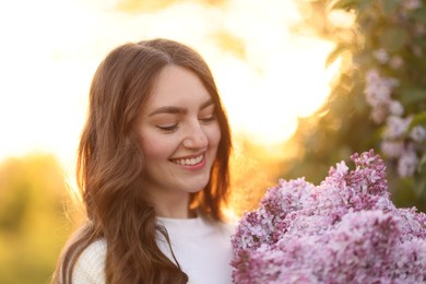 Photo of Smiling woman with bouquet of lilac flowers outdoors in morning, closeup