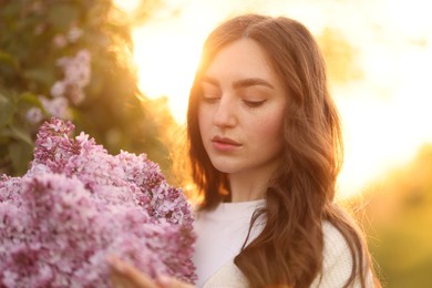 Photo of Beautiful woman with bouquet of lilac flowers outdoors in morning, closeup