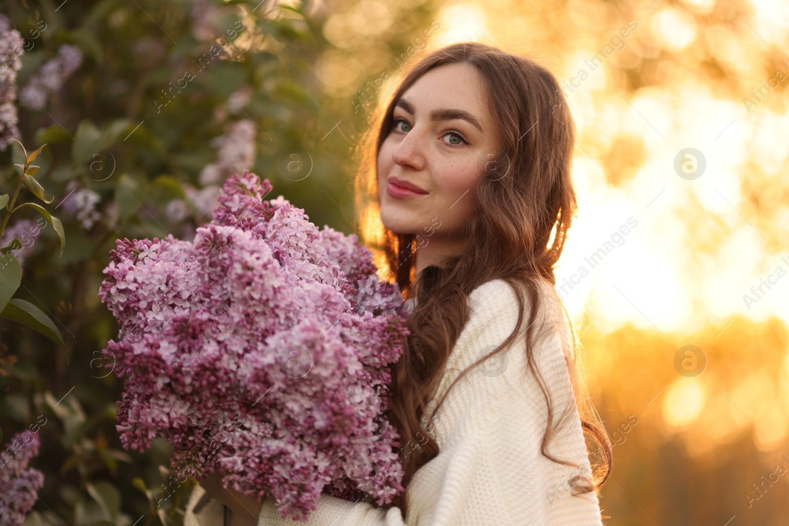 Beautiful woman with bouquet of lilac flowers outdoors in morning Photo of Beautiful woman with bouquet of lilac flowers outdoors in morning