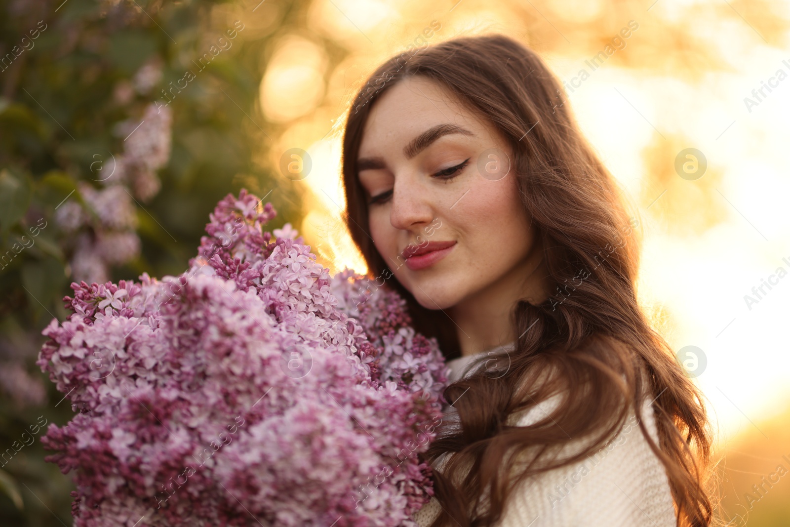 Beautiful woman with bouquet of lilac flowers outdoors in morning, closeup Photo of Beautiful woman with bouquet of lilac flowers outdoors in morning, closeup