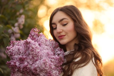 Photo of Beautiful woman with bouquet of lilac flowers outdoors in morning, closeup