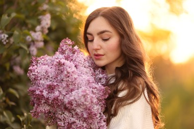 Photo of Beautiful woman with bouquet of lilac flowers outdoors in morning, closeup