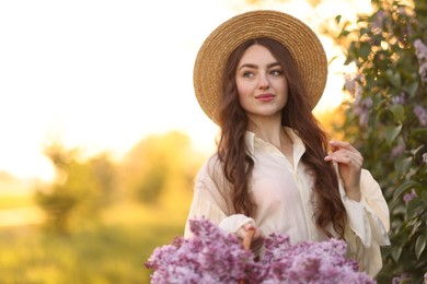 Photo of Beautiful woman with basket of lilac flowers outdoors in morning. Space for text