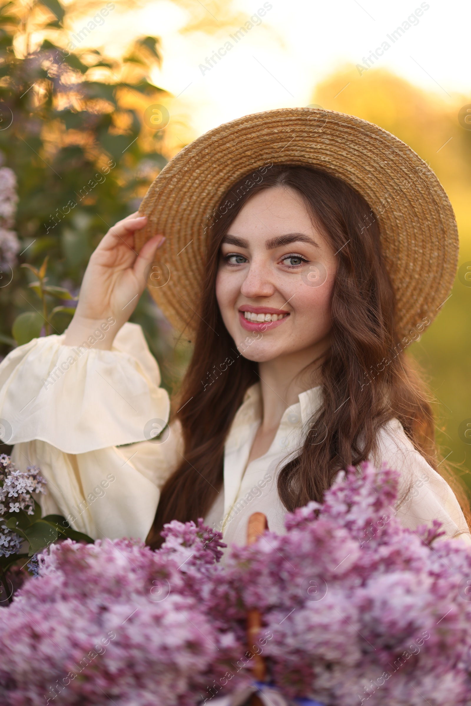 Portrait of smiling woman with lilac flowers outdoors in morning Photo of Portrait of smiling woman with lilac flowers outdoors in morning
