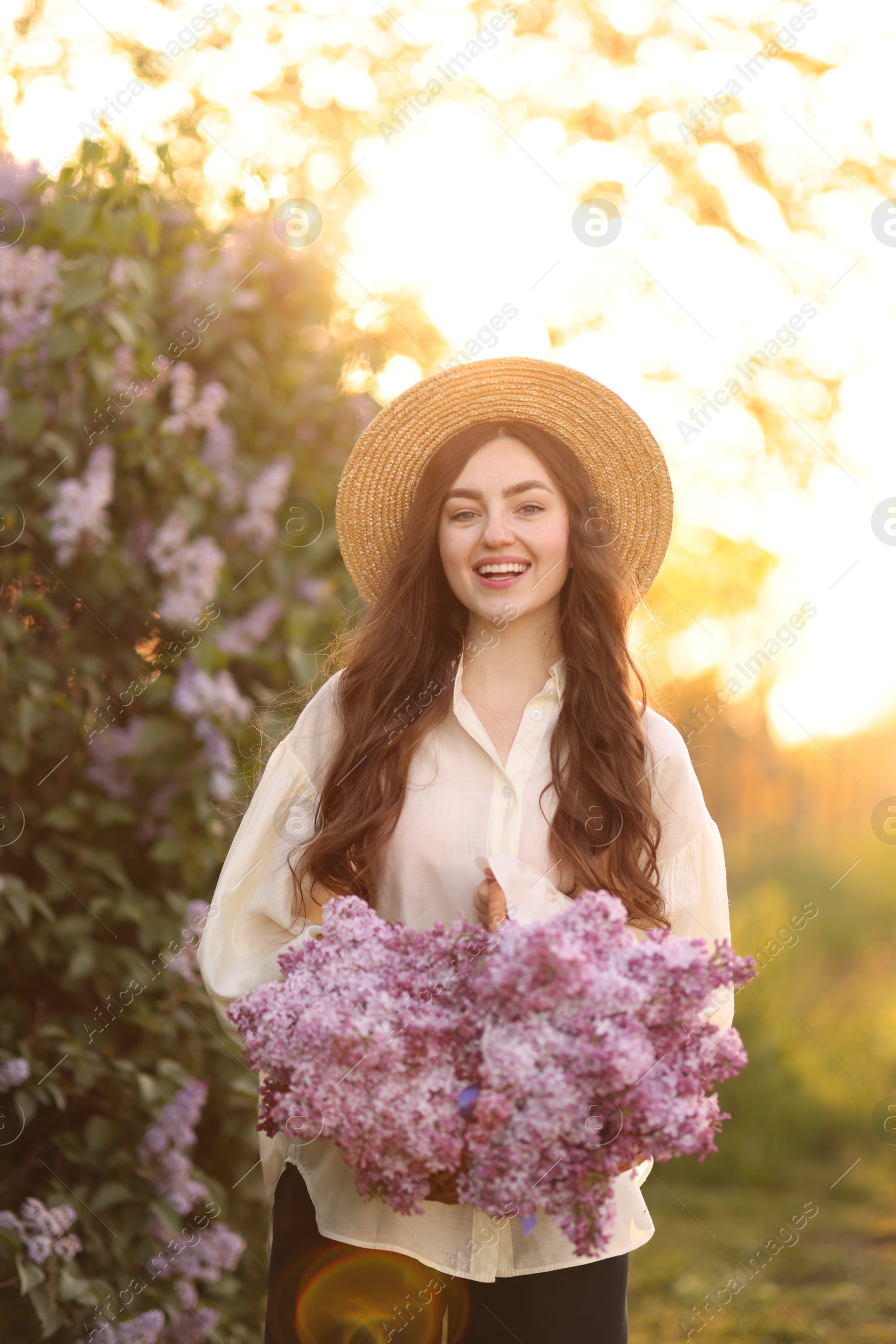 Portrait of smiling woman with lilac flowers outdoors in morning Photo of Portrait of smiling woman with lilac flowers outdoors in morning