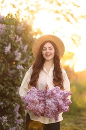 Photo of Portrait of smiling woman with lilac flowers outdoors in morning