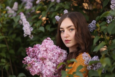 Photo of Portrait of beautiful woman with lilac flowers near bush outdoors