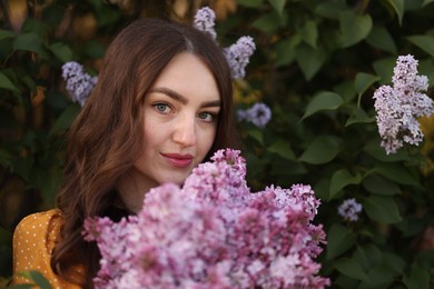 Photo of Portrait of beautiful woman with lilac flowers near bush outdoors
