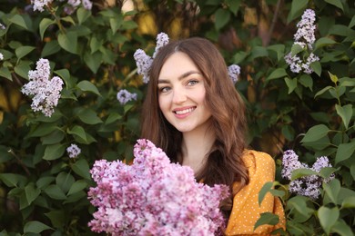 Photo of Portrait of smiling woman with lilac flowers near bush outdoors