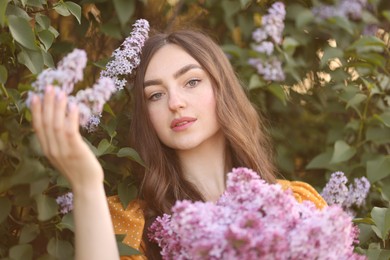 Photo of Portrait of beautiful woman with lilac flowers near bush outdoors