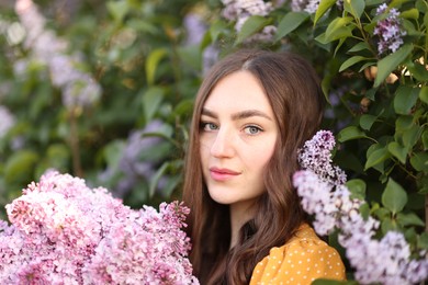 Photo of Portrait of beautiful woman with lilac flowers near bush outdoors
