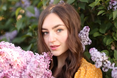 Photo of Portrait of beautiful woman with lilac flowers near bush outdoors