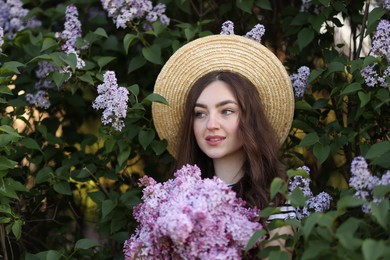 Photo of Smiling woman among lilac flowers and leaves outdoors