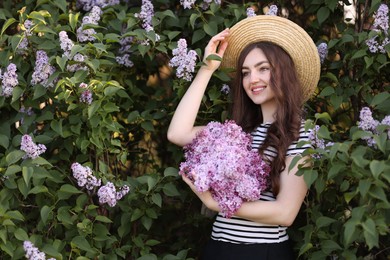 Photo of Smiling woman among lilac flowers and leaves outdoors