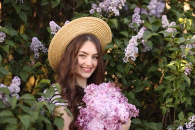 Photo of Smiling woman among lilac flowers and leaves outdoors