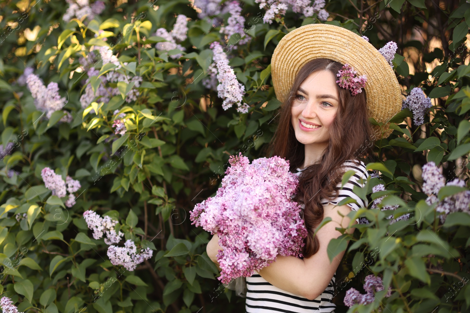 Smiling woman among lilac flowers and leaves outdoors Photo of Smiling woman among lilac flowers and leaves outdoors