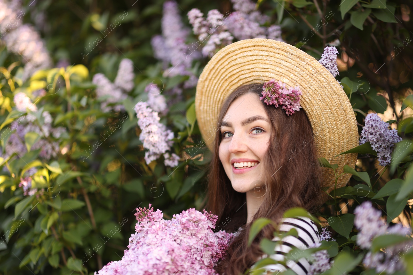 Smiling woman among lilac flowers and leaves outdoors Photo of Smiling woman among lilac flowers and leaves outdoors