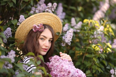 Photo of Beautiful woman among lilac flowers and leaves outdoors